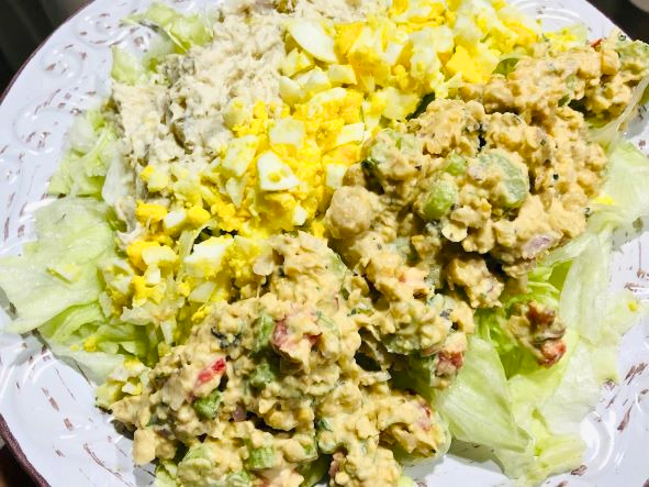 Smashed chickpea salad with chopped eggs and chicken on lettuce