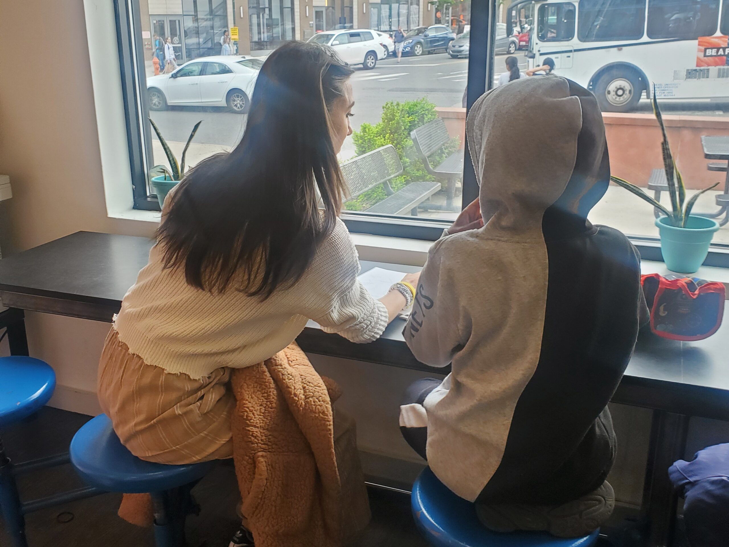 Tutor and child studying together indoors flooded in sunlight