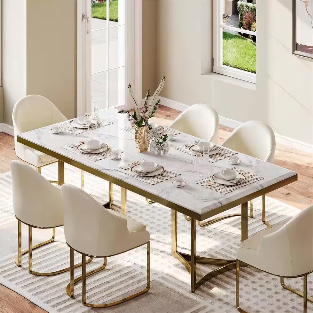 Large white marble table on gold legs with 8 beige chairs in a creamy and blush colored style dining room