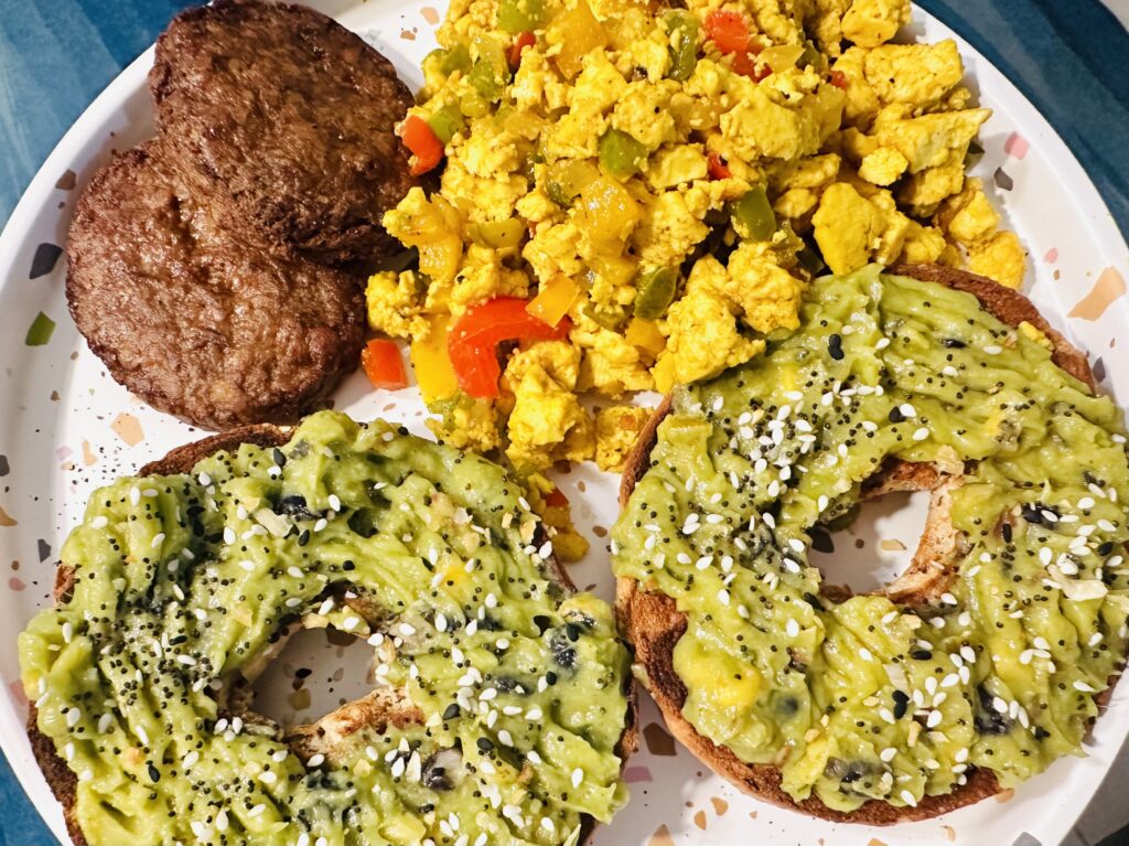 vegan tofu scramble with vegan sausage and bagel with guacomole