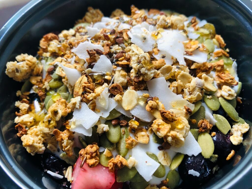 greek yogurt bowl topped with granola and berries and shaved coconut